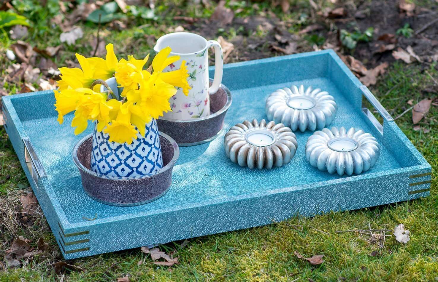 A set of three antique silver seed tea light holders on a blue shagreen serving tray