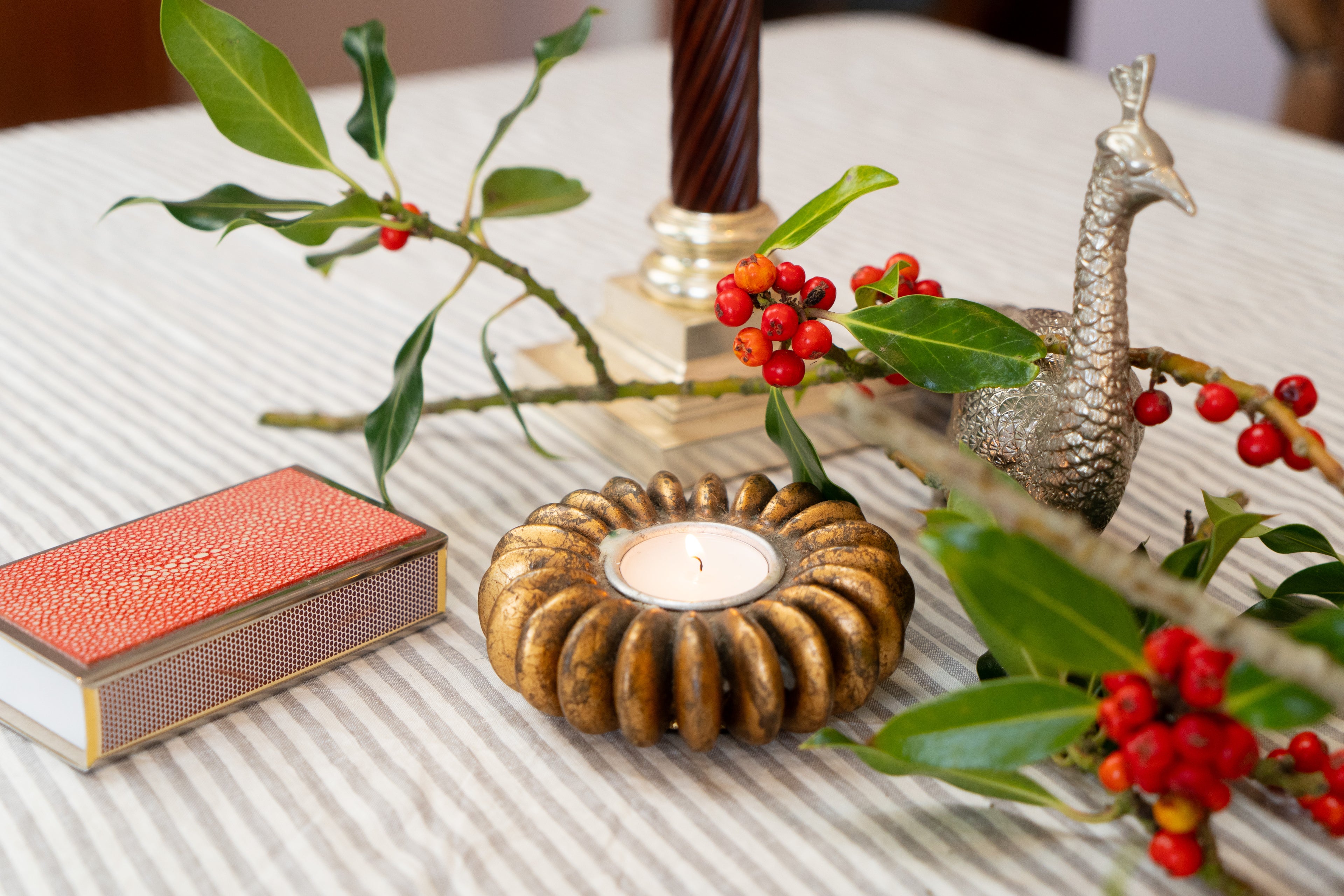 Decorative setup with a candle holder, peacock ornament and a matchbox holder