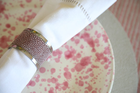 A close-up of a silver napkin ring with mulberry shagreen detailing